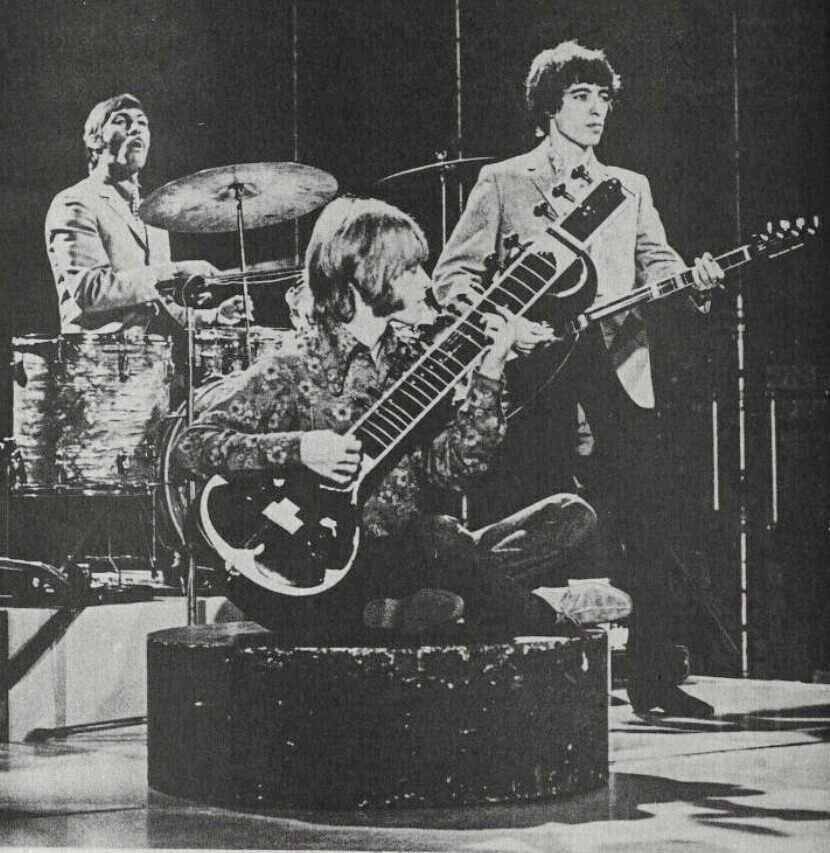 Brian Jones playing sitar onstage with Charlie Watts and Bill Wyman in the background, 1966